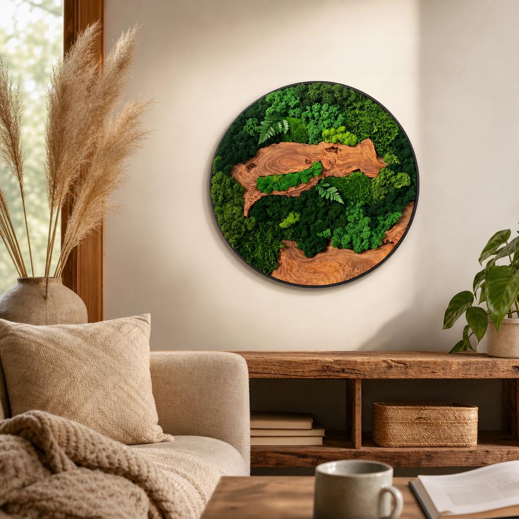 A circular wall art piece featuring a black frame enclosing a composition of preserved green moss and natural wood slices. The design incorporates various shades of green moss textures interspersed with smooth, light brown wood grain.