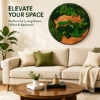 A circular wall art piece featuring preserved green moss and natural wood grain textures within a black frame. The text "ELEVATE YOUR SPACE" and "Perfect for Living Room, Office & Bedroom" is printed in dark green on the wall.