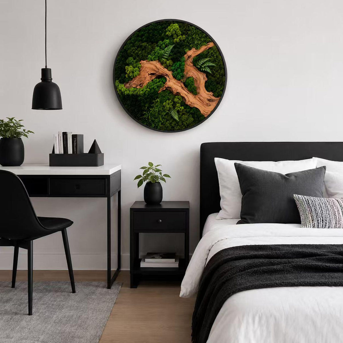 A circular wall art piece featuring a natural wood branch centerpiece surrounded by dense, vibrant green preserved moss and small fern fronds, all encased within a thin, black circular frame mounted on a plain white wall.