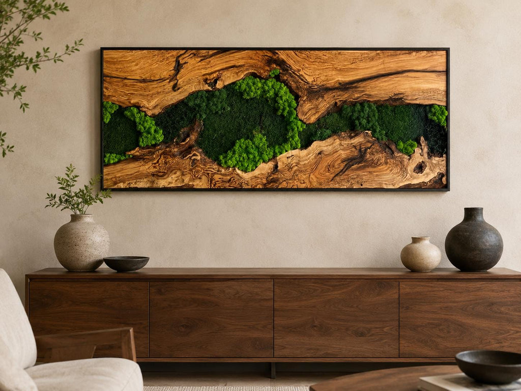 A rectangular wall art piece featuring a natural wood slab with a prominent grain pattern and a central crevice filled with vibrant green preserved moss, all enclosed within a thin black frame mounted on a neutral wall.