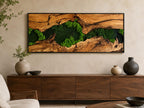 A rectangular wall art piece featuring a natural wood slab with a prominent grain pattern and a central crevice filled with vibrant green preserved moss, all enclosed within a thin black frame mounted on a neutral wall.