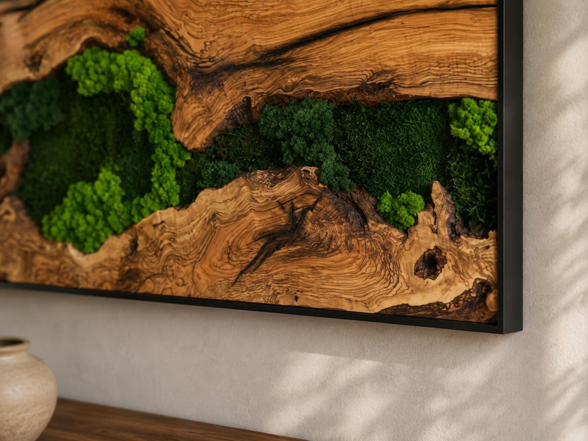 A rectangular wall art piece featuring a natural wood slab with a prominent grain pattern and dark knots, integrated with patches of vibrant green preserved moss. The entire composition is enclosed within a thin black metal frame.