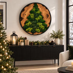 A circular wall art piece featuring a natural wood slice background with a tree-shaped arrangement of preserved green moss, enclosed in a thin black frame. The wood displays visible grain patterns and knots, contrasting with the moss.