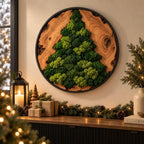 A circular wall art piece featuring a natural wood slice frame with a black metal border. The center displays a textured, three-dimensional Christmas tree shape crafted from preserved green moss in various shades of light and dark green.