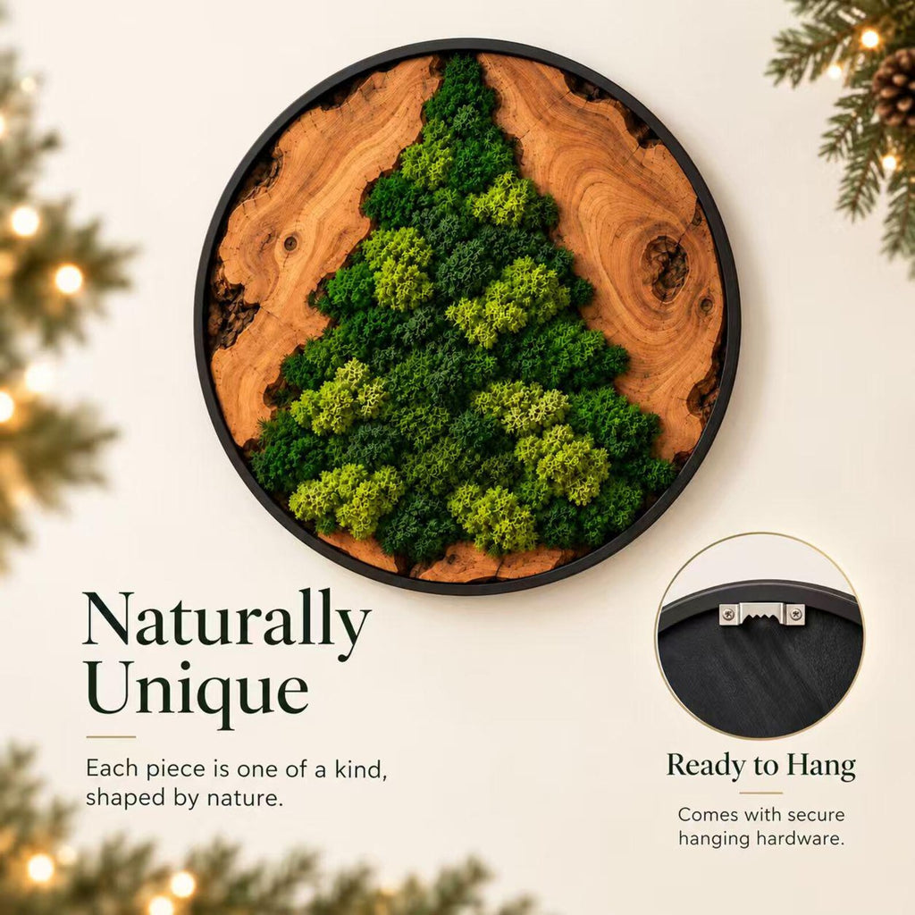A circular wall art piece featuring a natural wood slice base with a triangular arrangement of preserved green moss in the center. The wood slice is enclosed in a thin black frame. A metal sawtooth hanger is attached to the back.