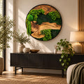 A circular wall art piece featuring a natural wood slice centerpiece surrounded by vibrant green preserved moss and fern foliage, all encased within a thin black frame. The composition displays varied textures of moss and wood.