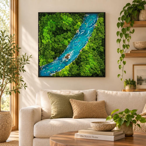 A square wall art piece featuring a preserved moss landscape with a central winding river made of blue resin. The artwork is encased in a thin black frame, displaying dense textures of bright green and dark green moss foliage.