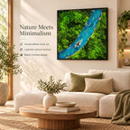 A square wall art piece featuring a vibrant green moss landscape with a winding blue river, encased in a black frame. The text reads: Nature Meets Minimalism, Handcrafted moss art, Layered natural texture, Black framed design.