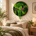 A circular wall art piece featuring preserved green moss and a piece of driftwood. The moss varies in shades of bright and dark green, with some sections hanging downward. The entire arrangement is contained within a thin, round frame.