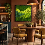 A square wall art piece featuring a dense arrangement of preserved moss in varying shades of vibrant lime, bright yellow-green, and deep forest green, framed in a thin black border and mounted on a solid terracotta-colored wall.