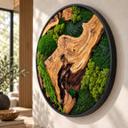 A circular wall art piece featuring a natural wood slab with prominent grain patterns, surrounded by preserved green moss and dark green fern fronds. The entire arrangement is encased in a thin, black circular metal frame.