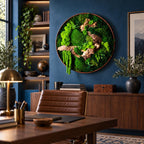 A circular wall art piece featuring preserved green moss and natural driftwood encased in a thin copper-toned frame. The arrangement displays various textures of vibrant green moss and light brown wood pieces in a dense composition.