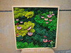 A square wall art piece featuring a light wood frame filled with preserved moss in various shades of lime, forest, and emerald green. The arrangement includes several small, reddish-brown, circular shelf fungi attached to the moss.
