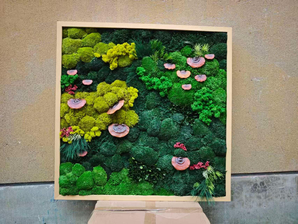 A square wall art piece featuring a dense arrangement of preserved moss in various shades of lime, forest, and emerald green. The composition includes several small, circular, reddish-brown shelf fungi and patches of fine, grass-like foliage.