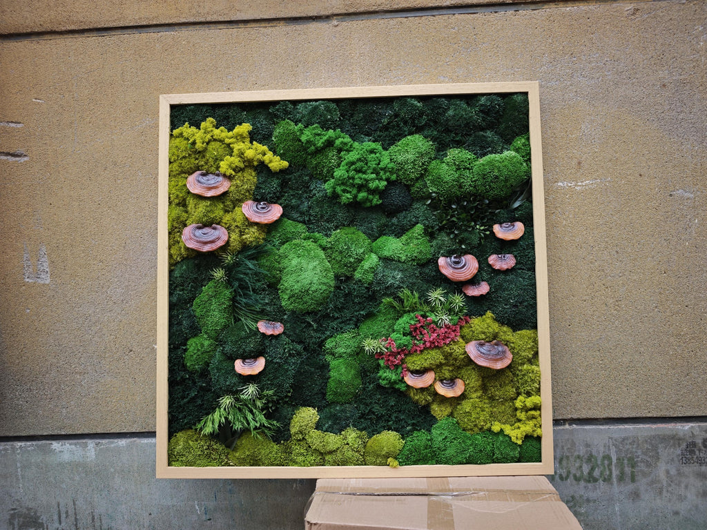 A square wall art piece featuring a dense arrangement of preserved green moss in various shades, including lime and dark forest green. The composition is accented with several small, circular, reddish-brown shelf fungi.