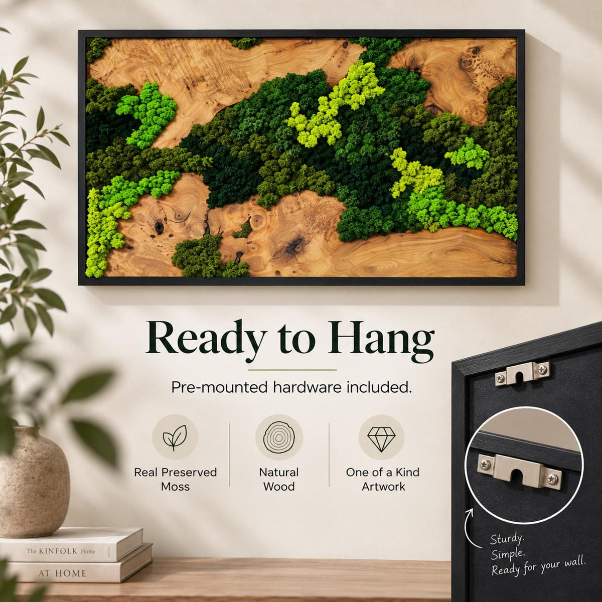 A rectangular wall art piece featuring a natural wood slab background with preserved moss in shades of lime green and dark forest green, enclosed in a black frame. The back of the frame includes metal mounting hardware for hanging.