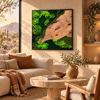 A square wall art piece featuring a natural wood slab with prominent grain patterns contrasted by vibrant green preserved moss in various shades, all encased within a thin black frame, mounted on a smooth beige wall.