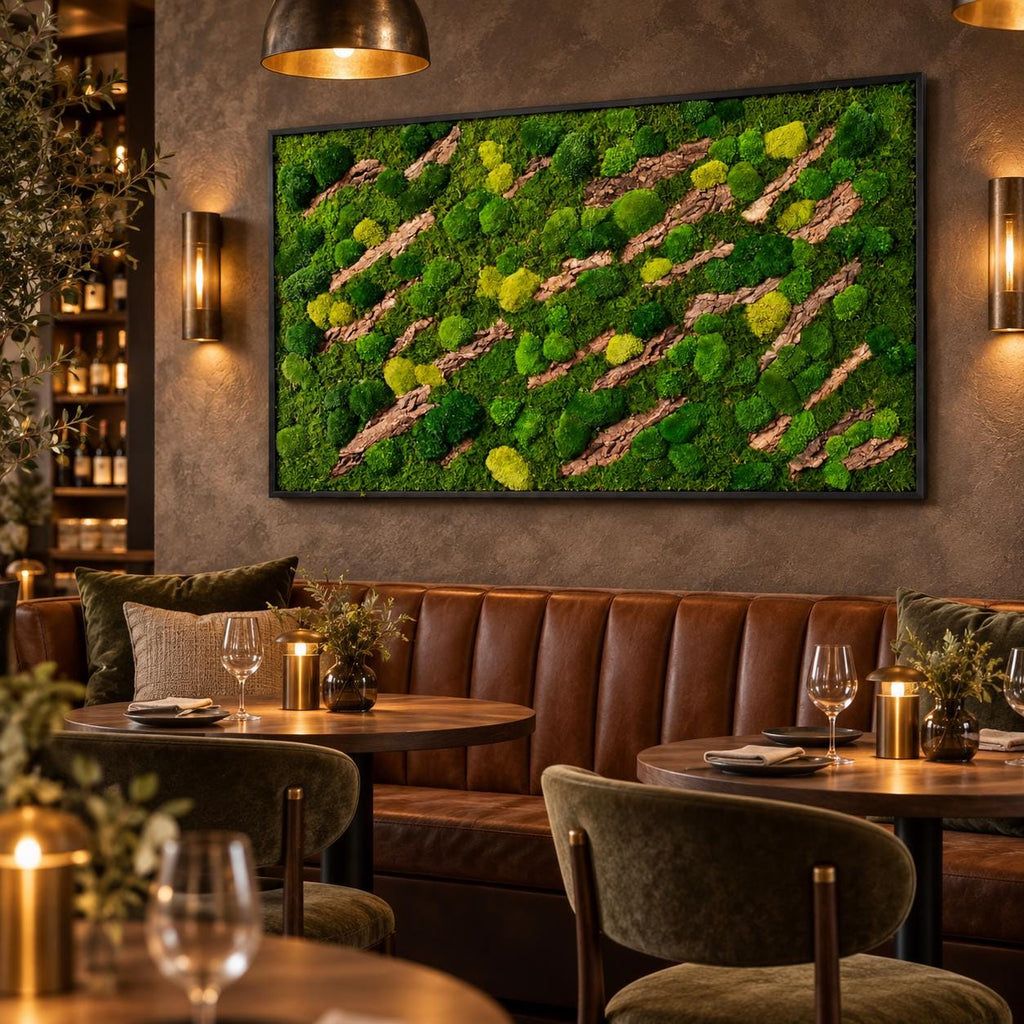 A rectangular wall art piece featuring a dense arrangement of preserved green moss in various shades, interspersed with diagonal strips of textured brown tree bark, all enclosed within a thin black frame mounted on a dark wall.