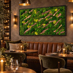 A rectangular wall art piece featuring a dense arrangement of preserved green moss in various shades, interspersed with diagonal strips of textured brown tree bark, all enclosed within a thin black frame mounted on a dark wall.