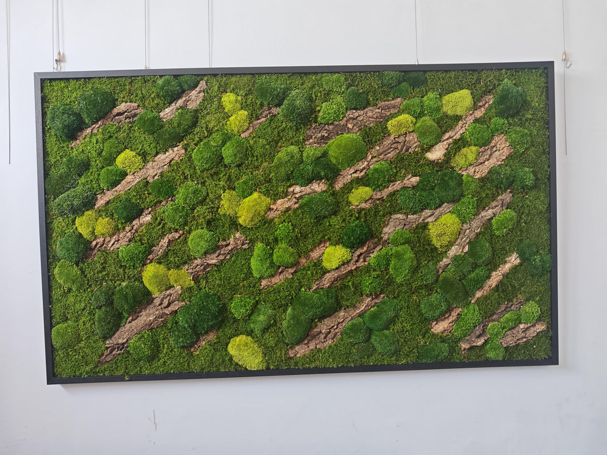 A rectangular wall art piece featuring a dense arrangement of preserved green moss in various shades, including bright lime and deep forest green, interspersed with diagonal strips of textured brown tree bark inside a black frame.