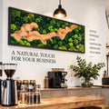 A rectangular wall art piece featuring preserved green moss and a central winding wood grain pattern in a black frame. The wall displays the text A NATURAL TOUCH FOR YOUR BUSINESS and a list of coffee drinks including COFFEE, ESPRESSO, LATTE.