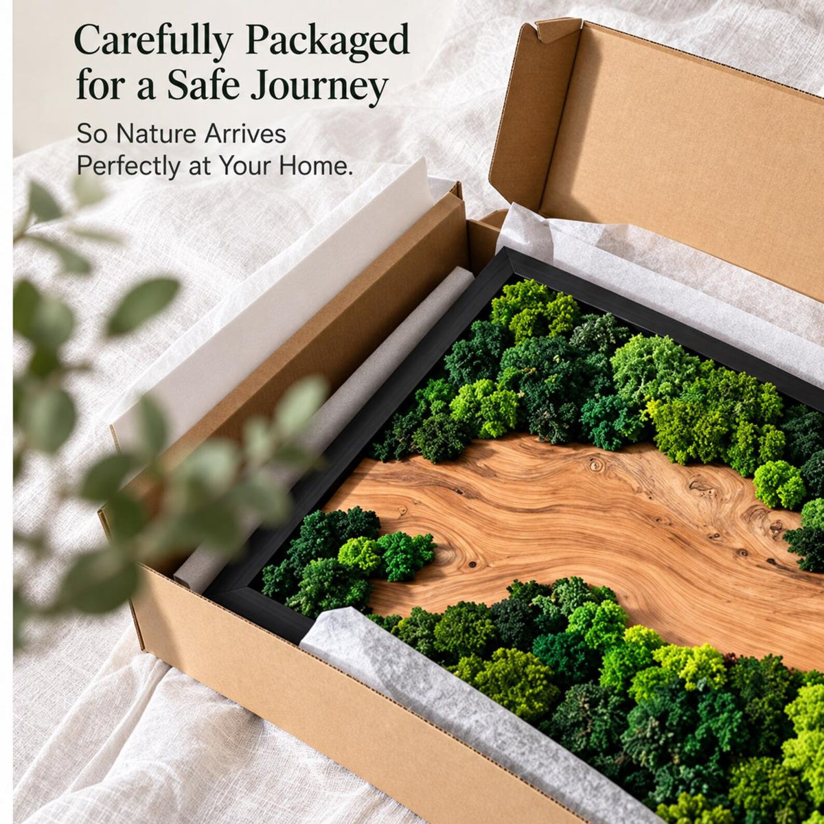 A rectangular wall art piece featuring a natural wood grain panel framed in black, decorated with clusters of preserved green moss. The item is inside a cardboard shipping box with the text Carefully Packaged for a Safe Journey.