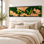 A rectangular wall art piece featuring a natural wood slab background with patches of preserved dark green and bright lime green moss, all enclosed within a thin black frame, mounted horizontally above a bed.